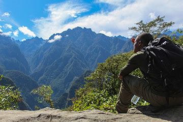 Editor Carleton Bailiff sitting on mountain looking at Machu Picchu mountains.